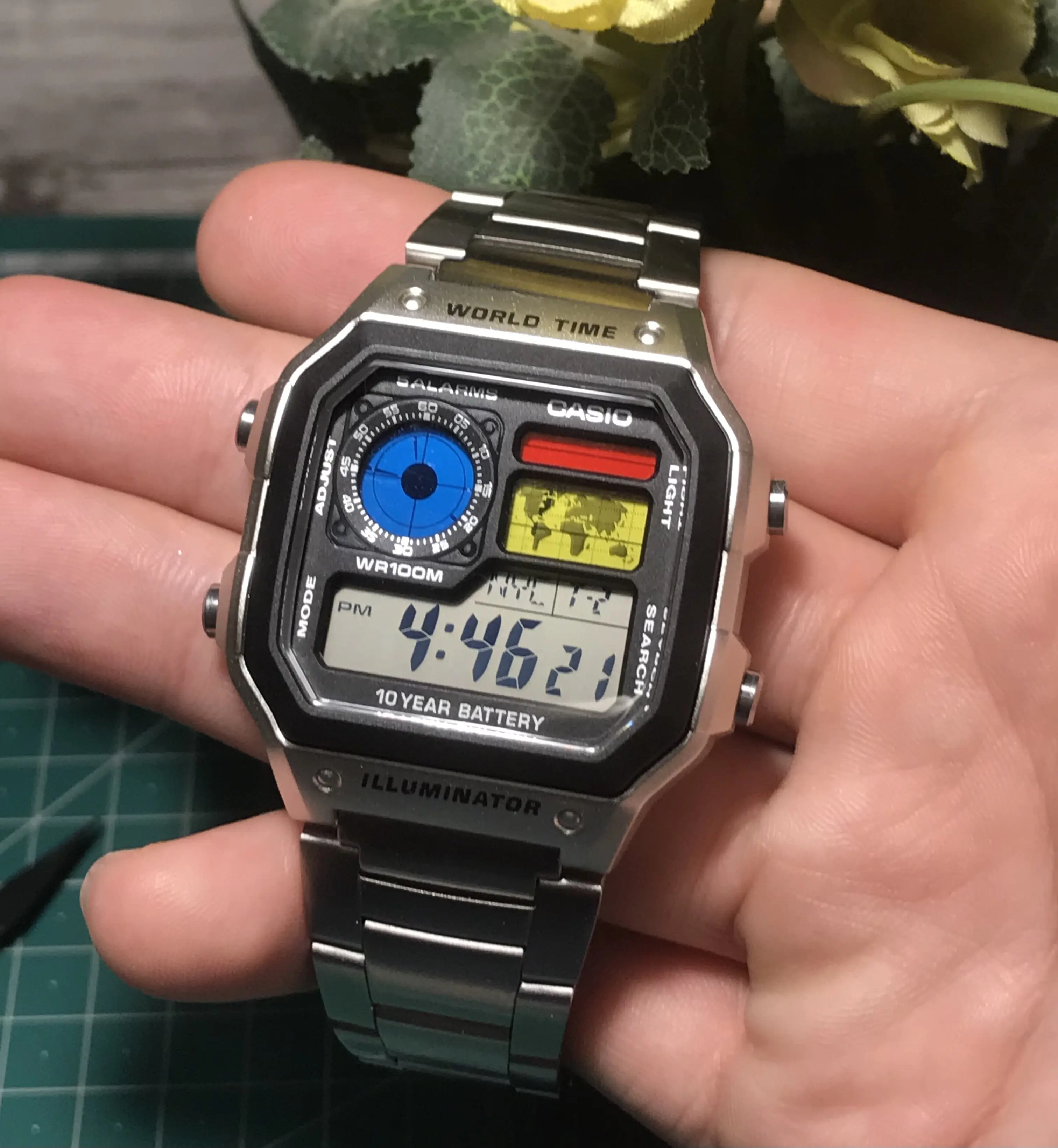 Hand holding Casio AE-1200 (Royale) The Command Center red blue yellow closeup